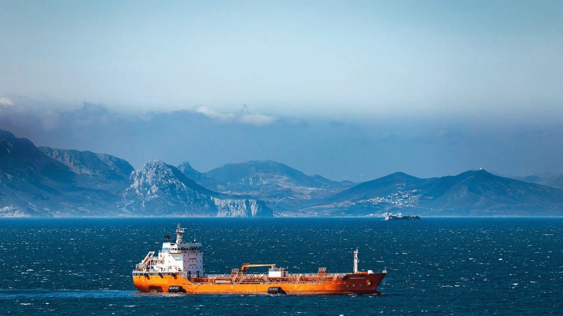 Starry night sky over the Strait of Hormuz with a cargo ship silhouette